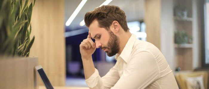 Homme assis à son bureau et se tenant la tête